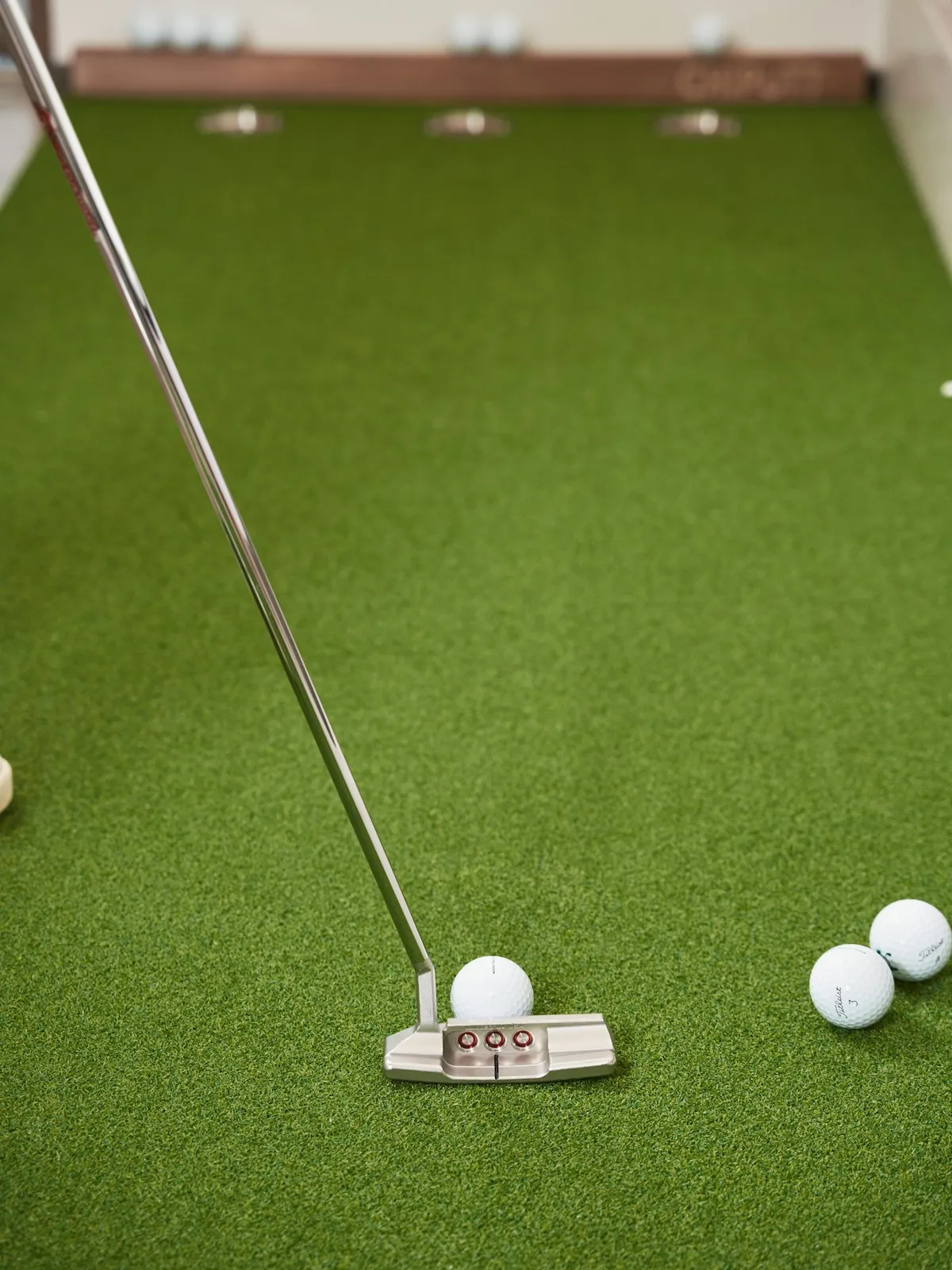 Golfer practicing putts on indoor putting green turf